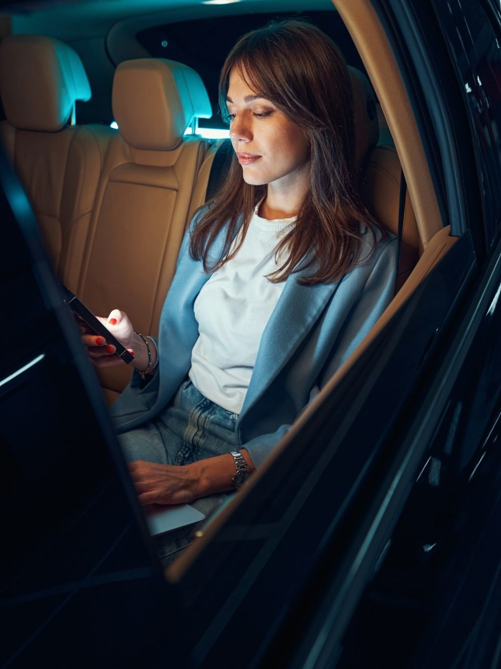 Woman sitting in automobile and using smartphone